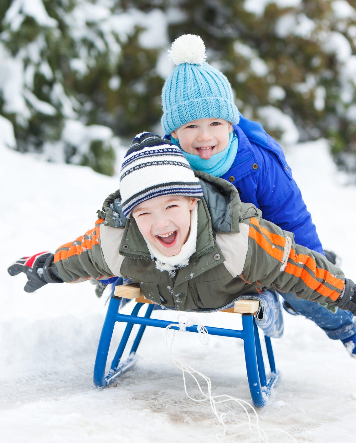 Children sledding down a snowy slope