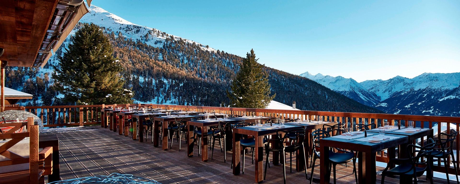 Terrace with wooden tables facing snowy peaks