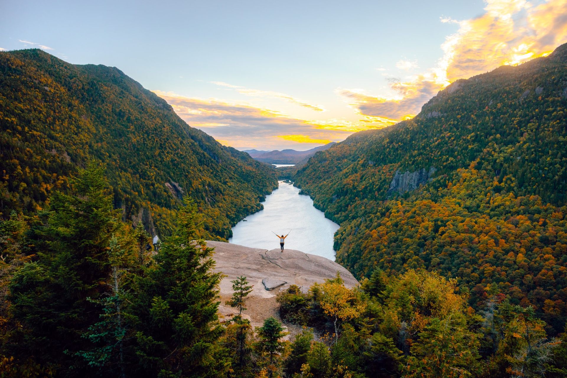 Hiker on a rocky ledge above a mountain valley